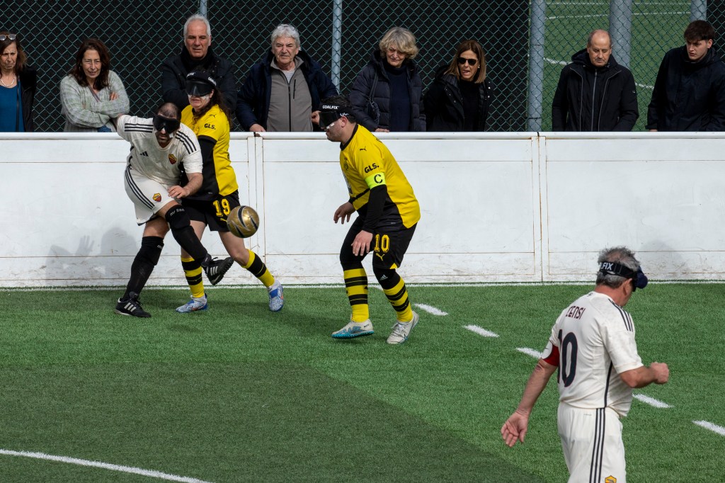 Campionato Europeo 2023 - 2024. Tappa Roma. In questa foto, un calciatore della Roma Blind Football, cerca di calciare il pallone allontanandolo dalla squadra avversaria che indossa un completo con pantaloncini color nero e maglietta color giallo.