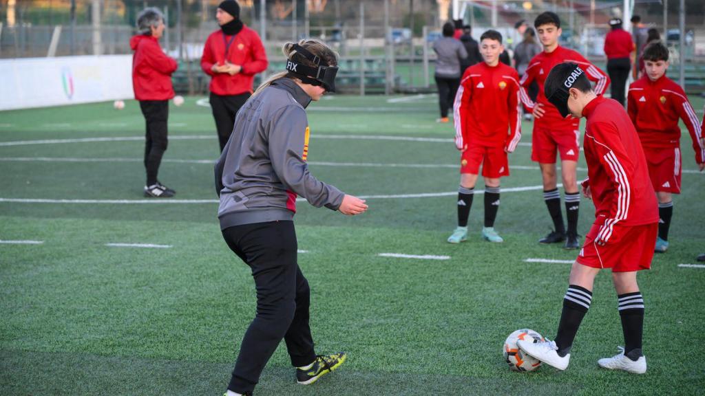 Giornata del Braille con AS Roma. Anno 2024. In questa foto un'atleta della Roma Blind Football con benda agli occhi, si passa il pallone con un bambino che ha anche la benda agli occhi